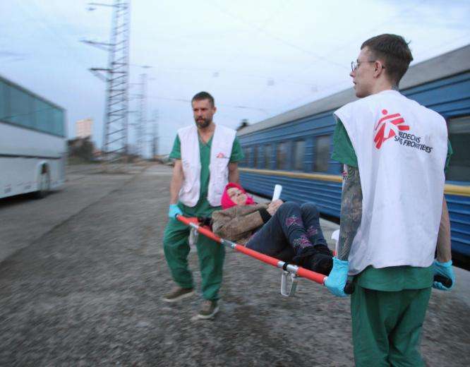 MSF staff members transport a patient from our medical train after its arrival in Lviv from Kramatorsk on April 7, 2022. The train evacuates patients in need of higher levels of care from hospitals close to the front lines.