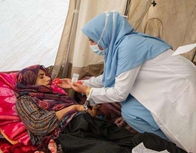 A female nurse gives an injured woman medication in an MSF emergency tent after the Afghanistan earthquake.