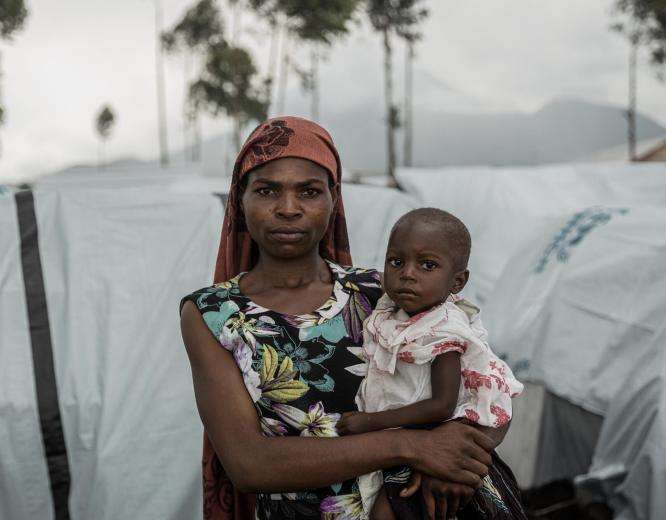 A woman holding a baby in a makeshift camp near Goma, Democratic Republic of Congo