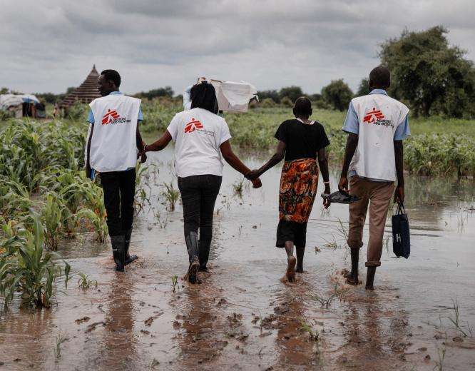 MSF staff members walk across a flooded area in South Sudan