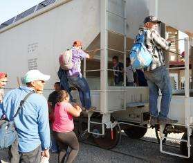 Men, women, and children board the moving train to reach the northern border of Mexico.