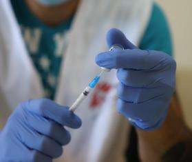 An MSF staff member in white vest and latex gloves prepares a dose of the COVID-19 vaccine at a nursing home in Lebanon.