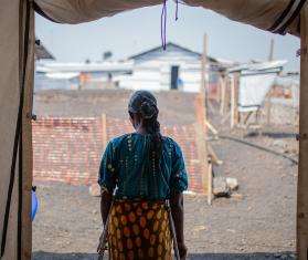 A woman stands in a makeshift tent facing away in a camp for displaced people near Goma, Democratic Republic of Congo.