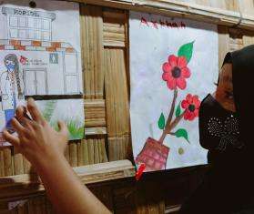 A young Rohingya refugee points to a picture she drew of an MSF doctor in a clinic.