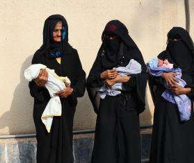 Three women carry babies outside Abs General Hospital in Yemen.