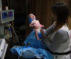 An MSF staff member in Gaza holds up a newborn baby at Nasser Hospital.