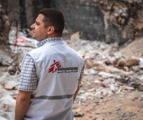 Dr. Sohaib Safi stands in front of the ruins of a residential tower destroyed by an Israeli airstrike in May 2021. r