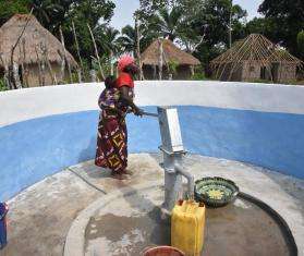 A woman uses a hand pump to get safe drinking water in Sierra Leone. 