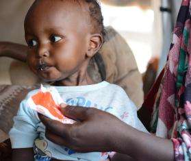 A child eats ready-to-use therapeutic food to treat malnutrition in Sudan.