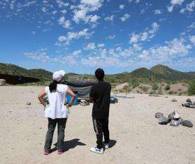 Project Coordinator Belen Ramirez and a 17-year-old boy form Bangladesh look at a helicopter flying overhead at the End of the Wall camp in Arizona.