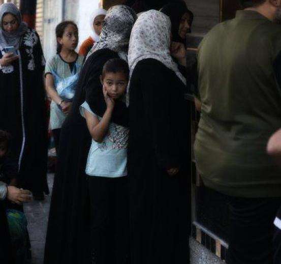 Palestinians line up for food and water in Gaza during the war with Israel in October 2023.