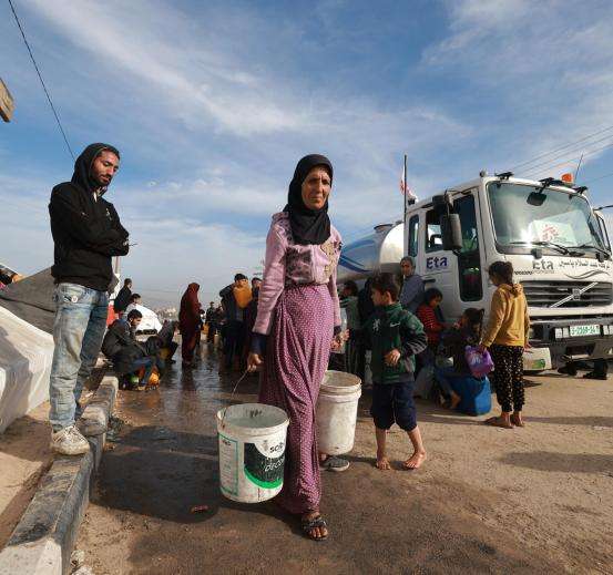 A Palestinian woman carries water to her tent after an MSF distribution in the coastal area of Mawasi Rafah, in the south of the Gaza Strip.