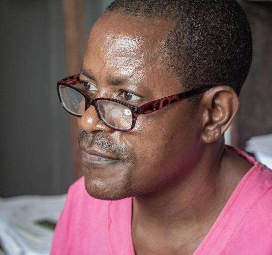 Man in dark pink shirt speaks at Walikale hospital. 