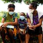 A child sits between two people in surgical masks after completing TB treatment from MSF in Papua New Guinea.