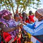 An MSF staff screens the child of a newly-arrived refugee family for malnutrition in their compound