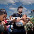 A migrant carries a small child with another beside him as he crosses the Darién Gap between Colombia and Panama.